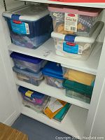 Photo of plastic bins filled with various sewing supplies stored on shelves.