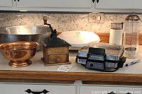 Overview of all items together on countertop, showing coffee grinders, bowls, waffle iron, and straw jar