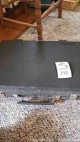 Closed black hard carrying case with handle for portable computer and cassette recorder.
