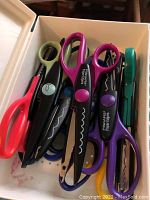 Close up of Fiskars decorative edge scissors showing various blade shapes and colors including purple and black handles