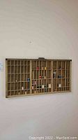 Front view of wooden printers tray mounted on wall with thread spools in compartments.