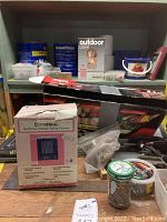 Photo shows a shelf with multiple boxes and containers including a boxed DuraHeat ceramic heater, hardware containers, and other boxed items including the reciprocating saw box partially visible.