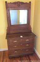 Front view of wooden carved dresser with three drawers and adjustable mirror above. Some visible wear and loose hardware handles on drawers.