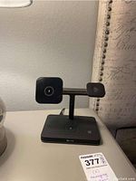 Photo showing front view of first black wireless charging station with dual angled pads and digital clock on base.