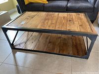 Full view of the rectangular coffee table showing wood plank top and black metal frame.