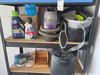 Lot shelf with Bissell SpotBot Pet cleaner, cleaning solutions, handheld vacuum, and bread maker.