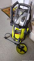 Full view of Sun Joe pressure washer showing yellow and black body, detergent containers, hose, and wand in folded position.