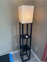Full view of the lamp showing white fabric shade and black shelves.