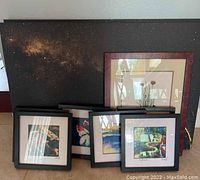 Nine pieces of wall art arranged with the largest starry night canvas at the back and smaller framed prints and floral art in front