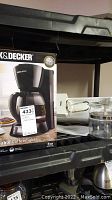 Photo of Black & Decker 12-cup programmable coffeemaker original packaging box on shelf.