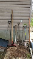 Full view of all garden tools leaning against wall (snow shovel, shovels, rake, hoe, log splitter)