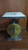 Full view of the vintage scale with brass dial and weighing platform.