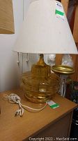 Full view of vintage amber glass table lamp with white fabric shade, showing shape and color.
