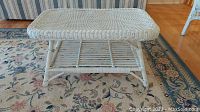 Front view of white wicker coffee table showing woven top and lower shelf