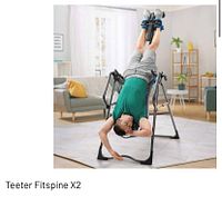 Main product image showing man using the Teeter FitSpine X2 inversion table in a living room setting