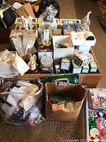 Overview photo showing multiple angel figurines and Christmas decorations in original boxes and loose, with packing materials nearby.
