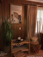 Overall view: bamboo serving cart on wheels, side table, stool and baskets against wood-paneled wall