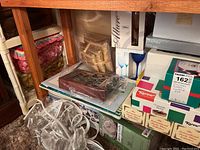 Photo showing boxed glassware including Libbey Allure blue stemmed glasses, Nagai Box, Karow Christmas-themed boxes, and some wrapped plates.