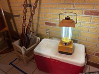 Wide shot showing Coleman cooler and yellow lantern light on top, wooden tray with forks next to cooler