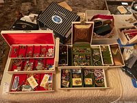 Wide shot showing two open jewelry boxes filled with assorted costume jewelry on a bed surface.
