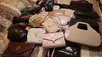 Multiple assorted handbags and clutches arranged on bed, showing overall assortment