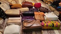 Full overview of all fourteen handbags arranged on bedding