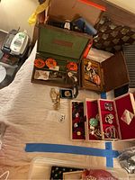 Overhead view of multiple jewelry boxes, watches, pins and sewing notion box on bed