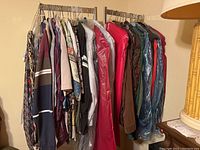 Photo of a clothes rack holding several men's clothing items including shirts, jackets, and pants in various colors and patterns.