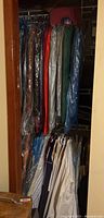 Closet rod with multiple plastic-bagged suits and shirts