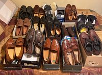 Fourteen pairs of men’s size 10 shoes and slippers arranged in boxes on a bed