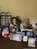 Wide view of lot showing assortment of perfumes, vanity trays, candles, decorative items, and a walking cane/frame.