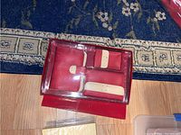 Red and cream Liz Claiborne wallet set in plastic case on floor