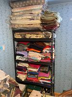 Front view of shelving unit with linens, blankets, folded clothing stacked on shelves