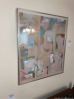 Side view of one framed abstract art piece with muted pastel colors and geometric face shapes