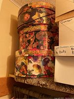 Stack of three floral-patterned round decorative hat boxes with handwritten season/color labels