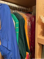 Photo of several women's tops in assorted colors hanging on a rod including blue, green, yellow, and red, some in protective garment bags