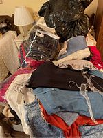 Pile of assorted women’s clothing and bags on bed