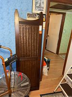 Single wood and woven panel room divider section leaning against wall