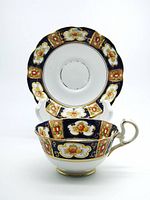 Top view of empty saucer with teacup resting inside showing scalloped rim and detailed painted decorations.