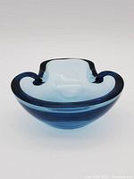 Front view of the blue folded glass bowl showing its curved folded edges and swirl design.