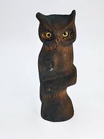 Front view of the dark stained, hand carved wooden owl sculpture showing yellow eyes and a small scuff on the front wing.