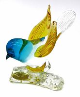 Front angle showing blue head, amber wings, clear textured glass base with gold foil label