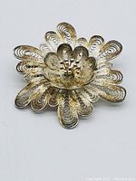 Top view of ornate handmade sterling silver filigree floral brooch with detailed petals and central stamen design.