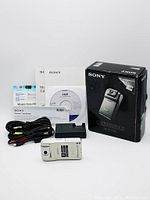 Sony MHS-PM1 Mobile HD Snap Camera with charger, cables, paperwork, CD, and original box displayed on white background.