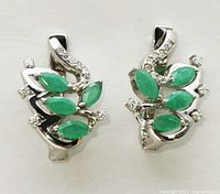Front view of both earrings laid flat showing rhodium-plated sterling silver, marquise-cut emeralds and pave-set cubic zirconia accents.