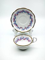 Teacup and saucer set, angled view showing chip on teacup rim and detail on floral pattern