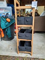 Front view of bamboo shelving unit holding six black collapsible fabric bins, two bins per shelf on three shelves, with no bins on top shelf.