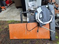 Photo showing side view of Black & Decker 10 inch radial arm saw on orange table surface with power cord and manual.