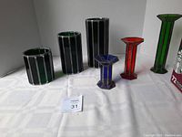 Photo showing full set of six leaded stained glass candle holders and candlesticks on a white surface.