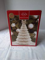 Box showing Lenox brand with image of the porcelain light-up tree and note that it is new and lights up.